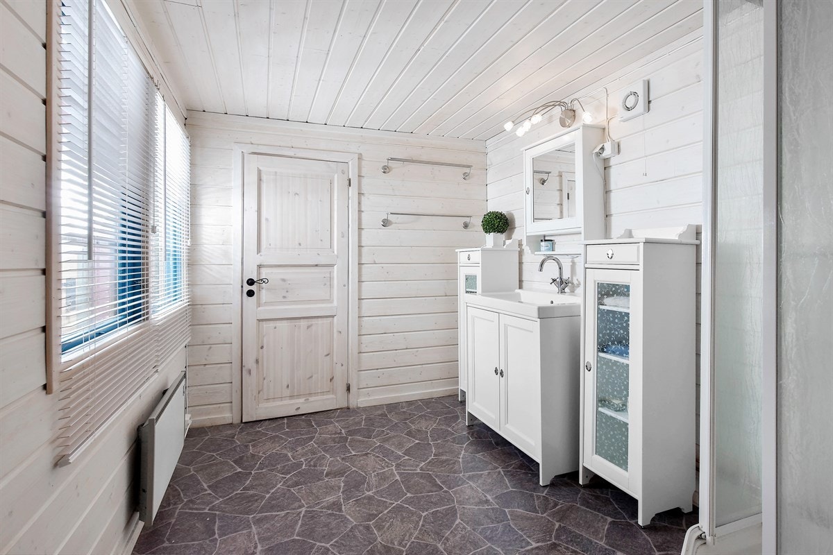 Badet er lyst og trivelig med lysbeisede panelte overflater og belegg i flisimmitasjon på gulv. Galleribilde