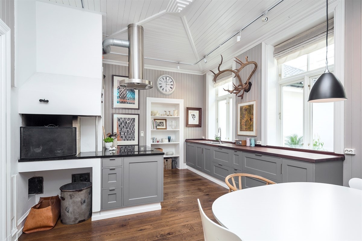 Kjøkken i lekker utførelse med integrerte hvitevarer, kjølehjørne og murt gruepeis Galleribilde