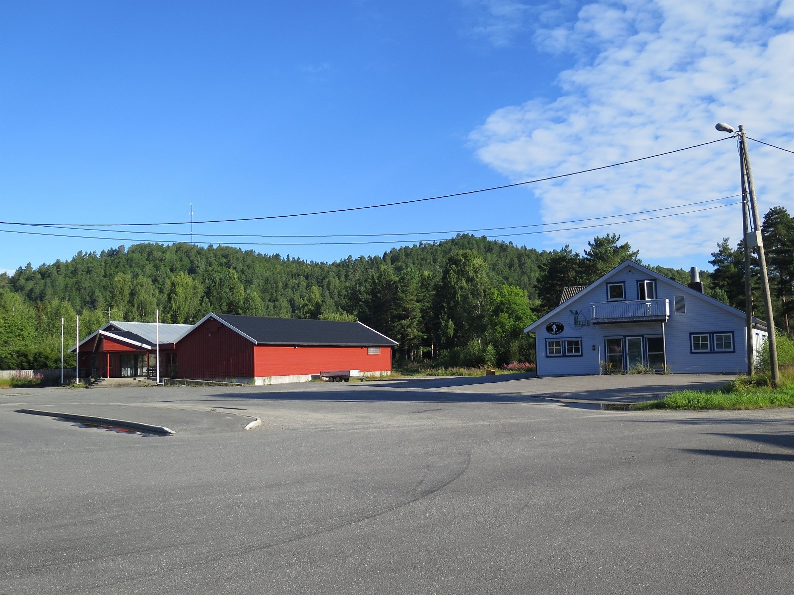 Innkjøring til eksisterende næringsbygg. Næringsarealet ligger i bakkant av rød bygning. Galleribilde