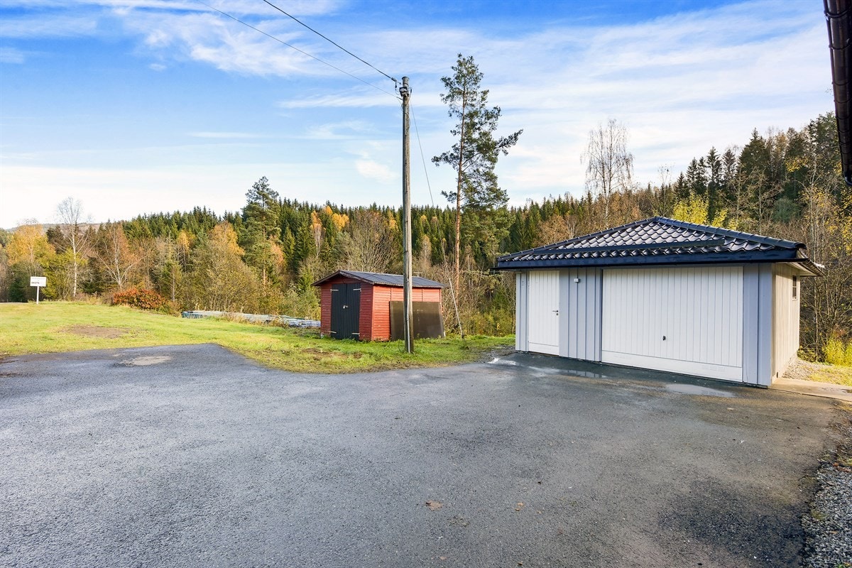 Det er parkering i en isolert garasje med elektrisk vippeport i tre, inngangsdør i front og god lagringsplass. Galleribilde