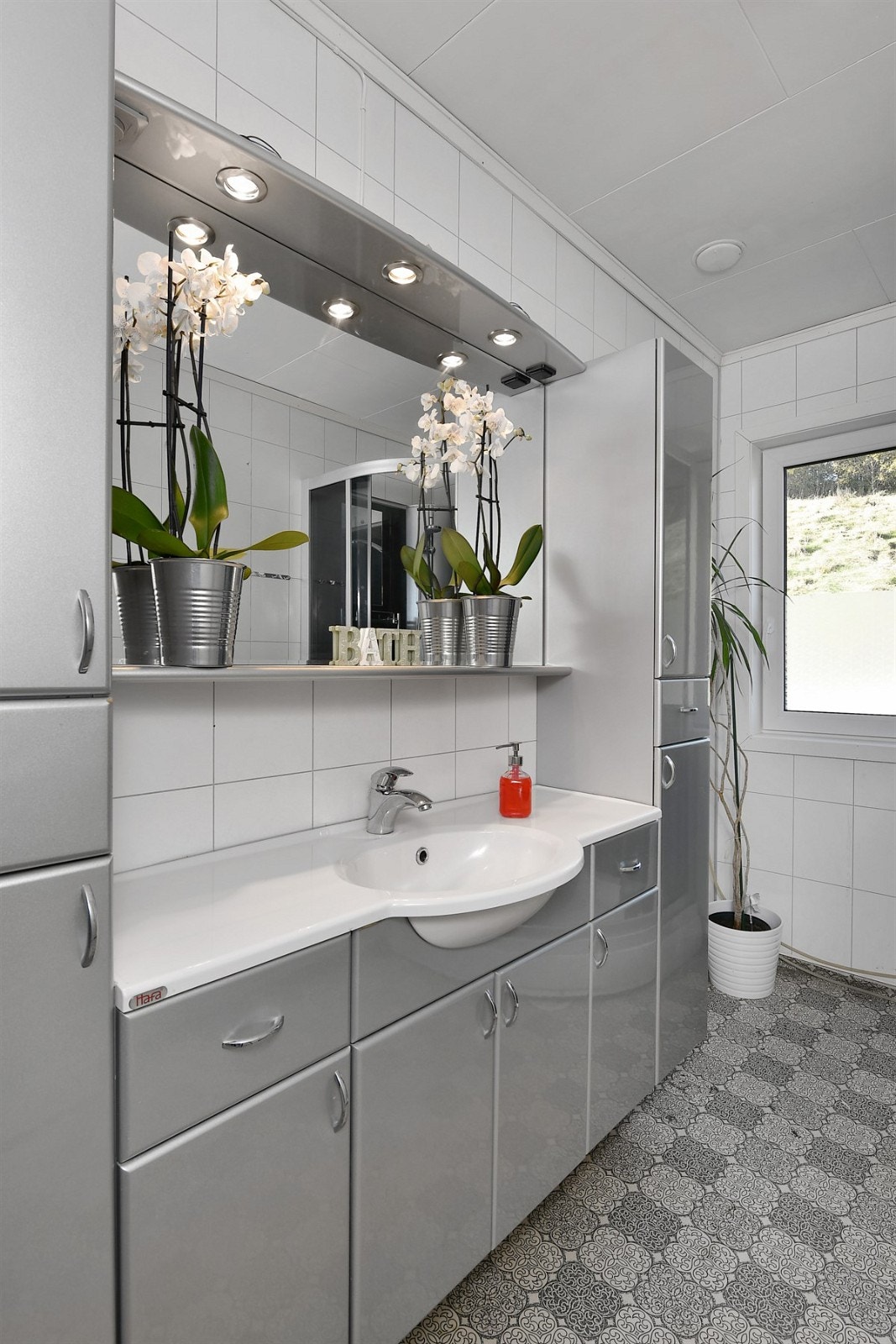 Badet i første etasje har belegg på gulv, baderomsplater med flismønster på vegger, gulvvarme og lysinnslipp fra vindu. Galleribilde