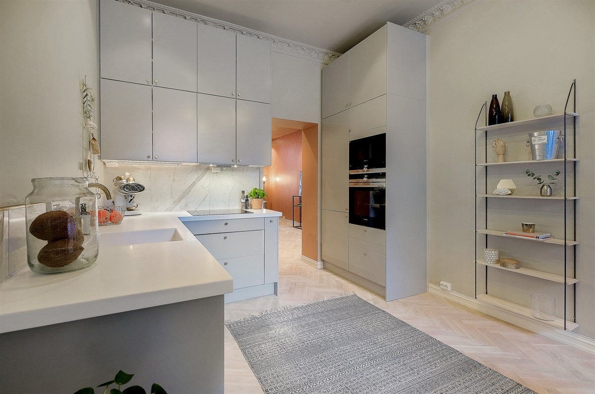 Kjøkkeninnredningen er moderne med grå matte fronter og hvit kompositt benkeplate. Galleribilde