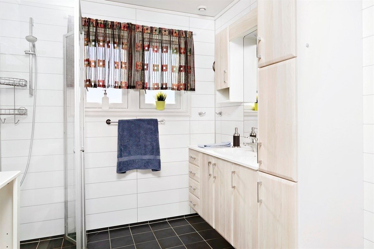 Badet har fliser på gulv og plater på vegg. Galleribilde