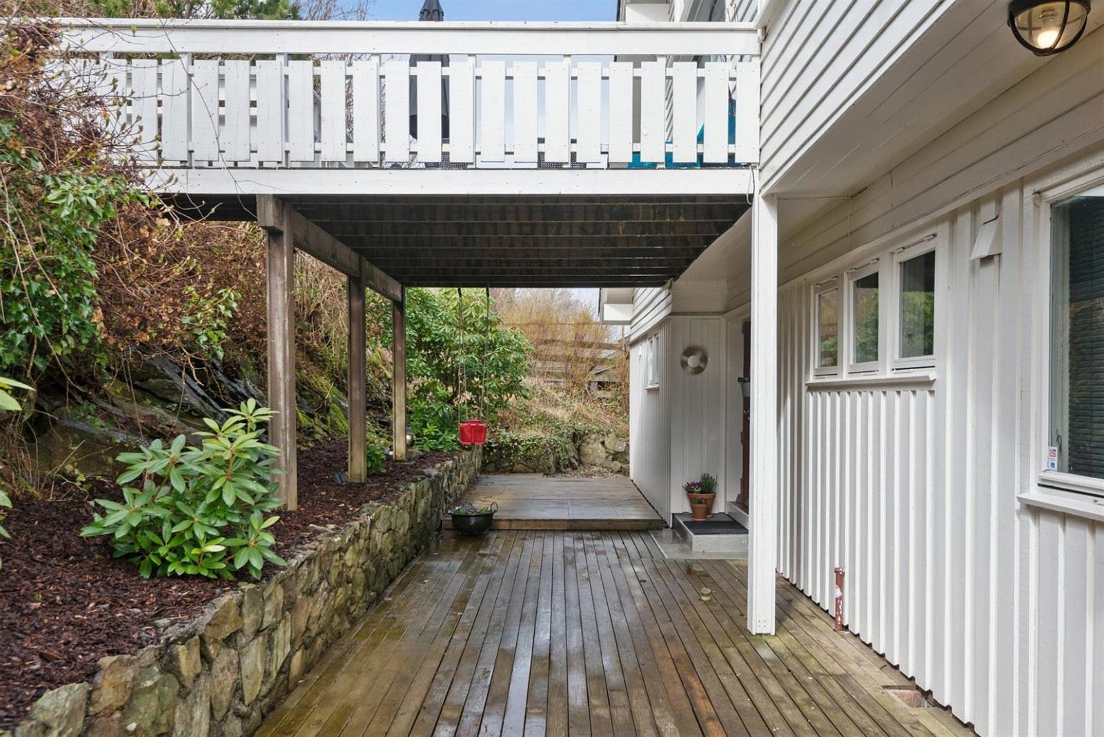 Inngangspartier er på baksiden og med natursteinmur mot skråningen og flott beplatning så oppleves området som en grønn liten oase på vår og sommer. Galleribilde