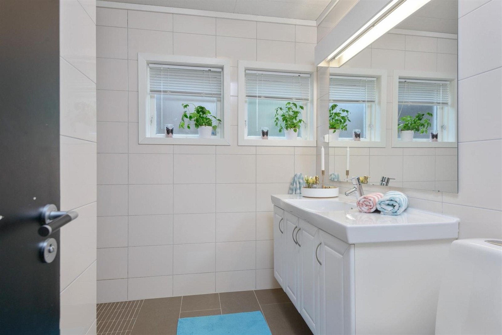 Et av husets to bad ligger selvfølgelig også i første etasje. Helfliset med varme i gulvet. Galleribilde