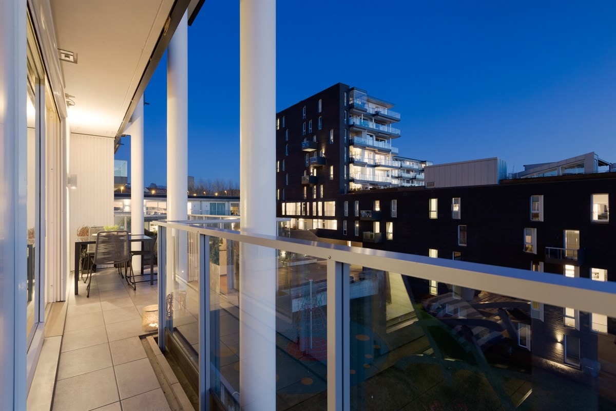 Balkongen strekker seg rundt to sider av leiligheten, og fungerer som en naturlig forlengelse av stuen i sommerhalvåret Galleribilde