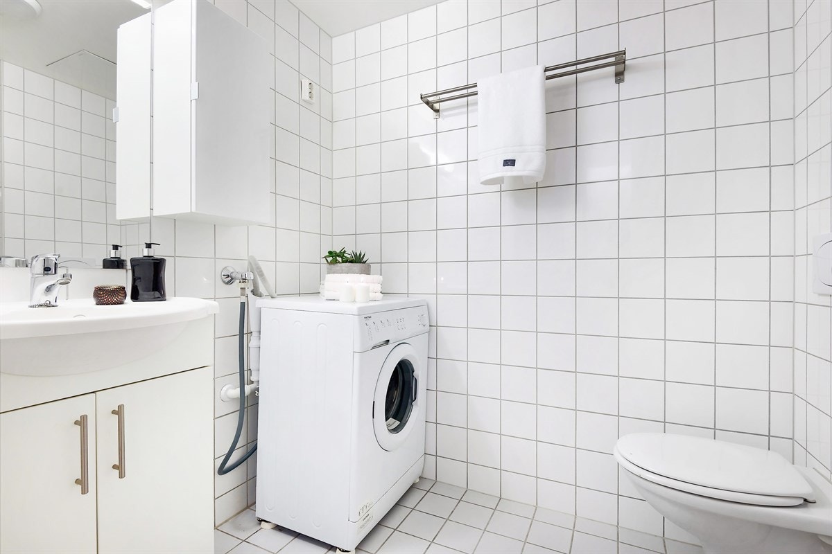 Pent flislagt baderom med opplegg for vaskemaskin og tørketrommel samt varmekabler Galleribilde