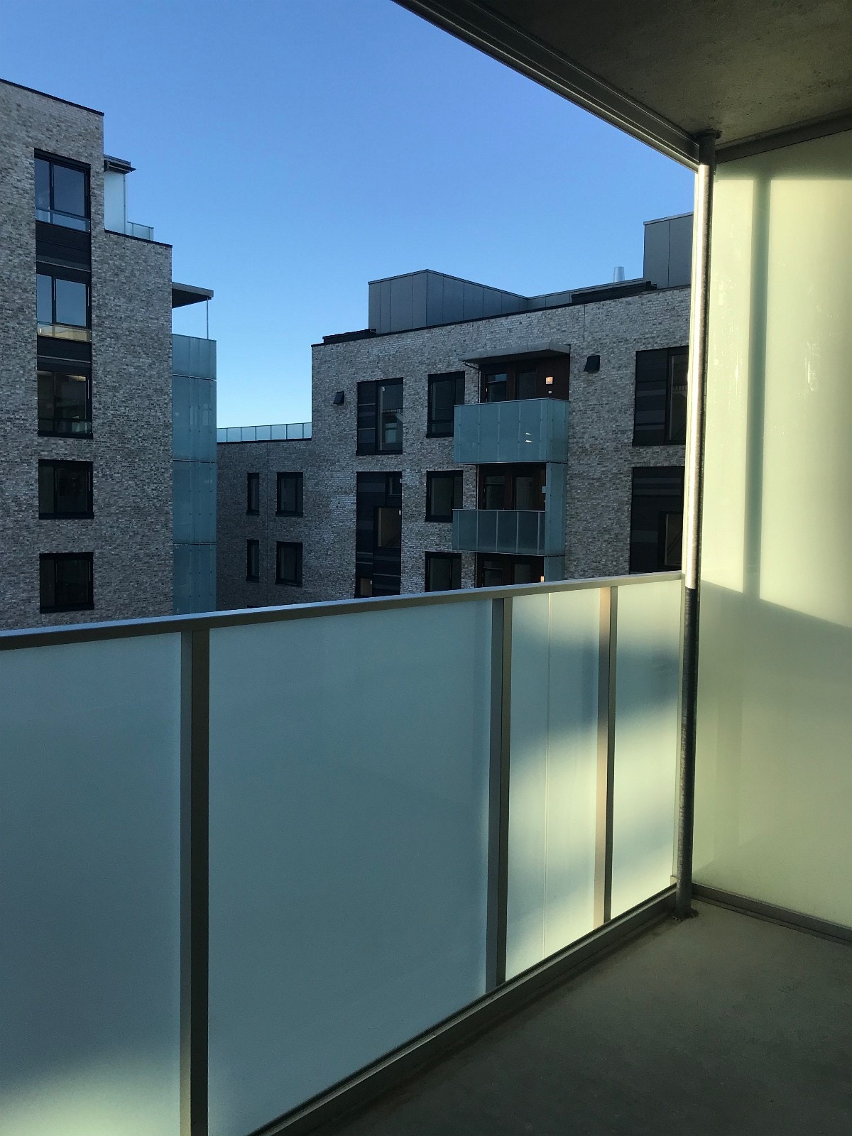 Balkongen har glassrekkverk og skyvbare glassfelt Galleribilde