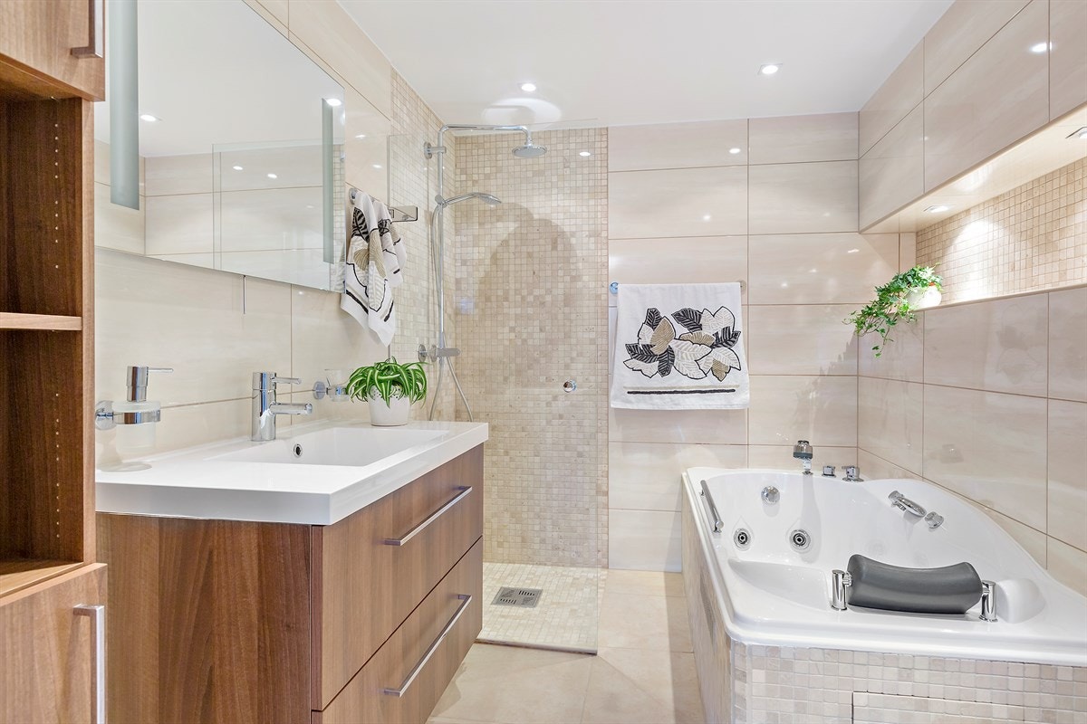 Lekkert bad med innfliset boblebad og et stilig dusjhjørne med mosaikkfliser Galleribilde