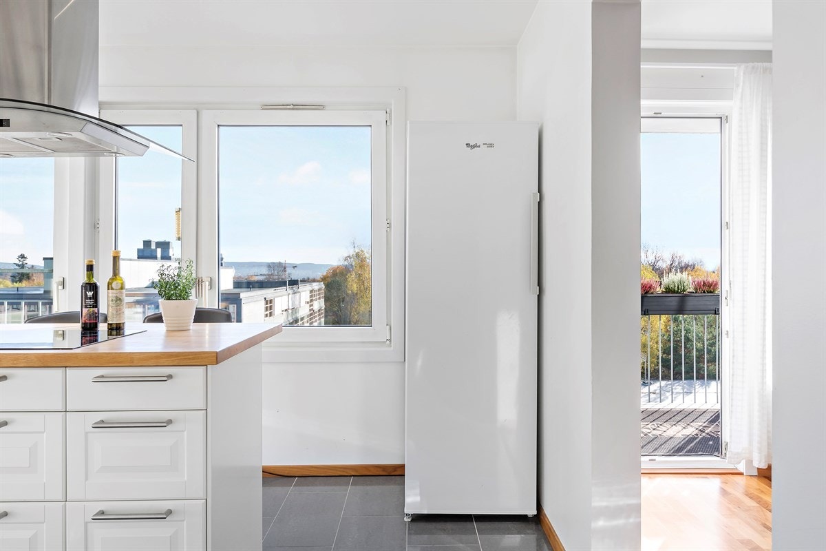 Innredningen har profilerte fronter og er utstyrt med vitrineskap, benkebelysning, fliser over heltre benkeplater i eik, downlights belysning og enkel vaskekum Galleribilde