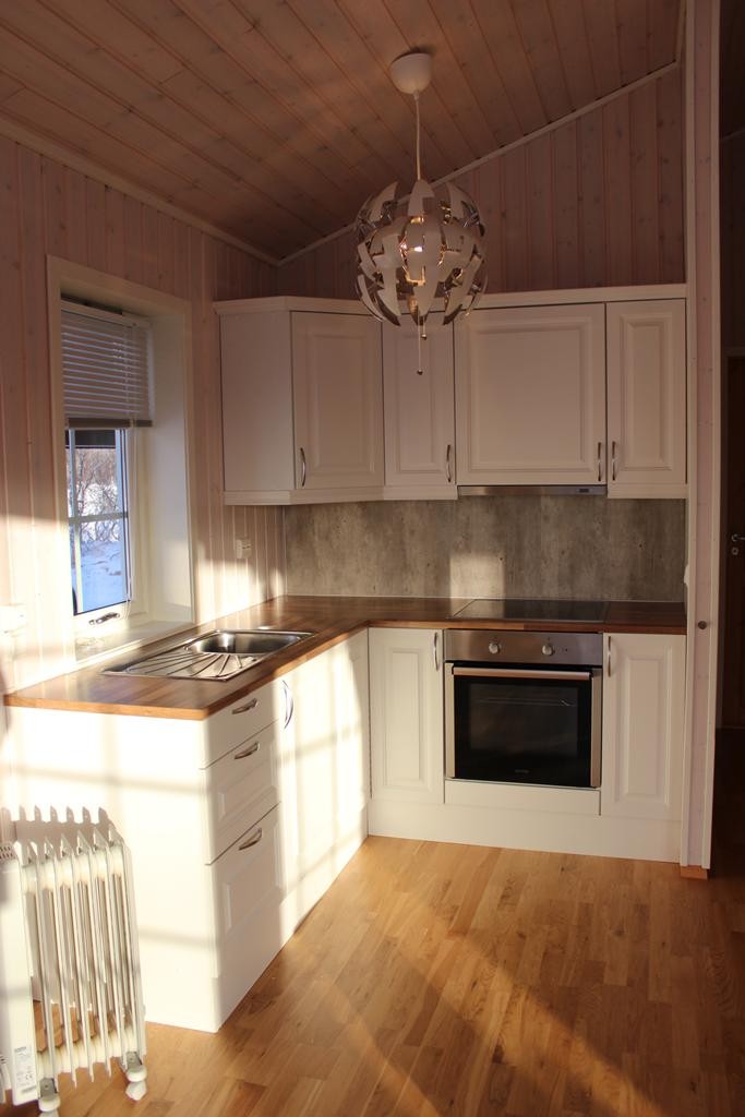 Hvit profilert kjøkkeninnredning, lekker benkeplate i laminat og kitcheboard i sement look Galleribilde