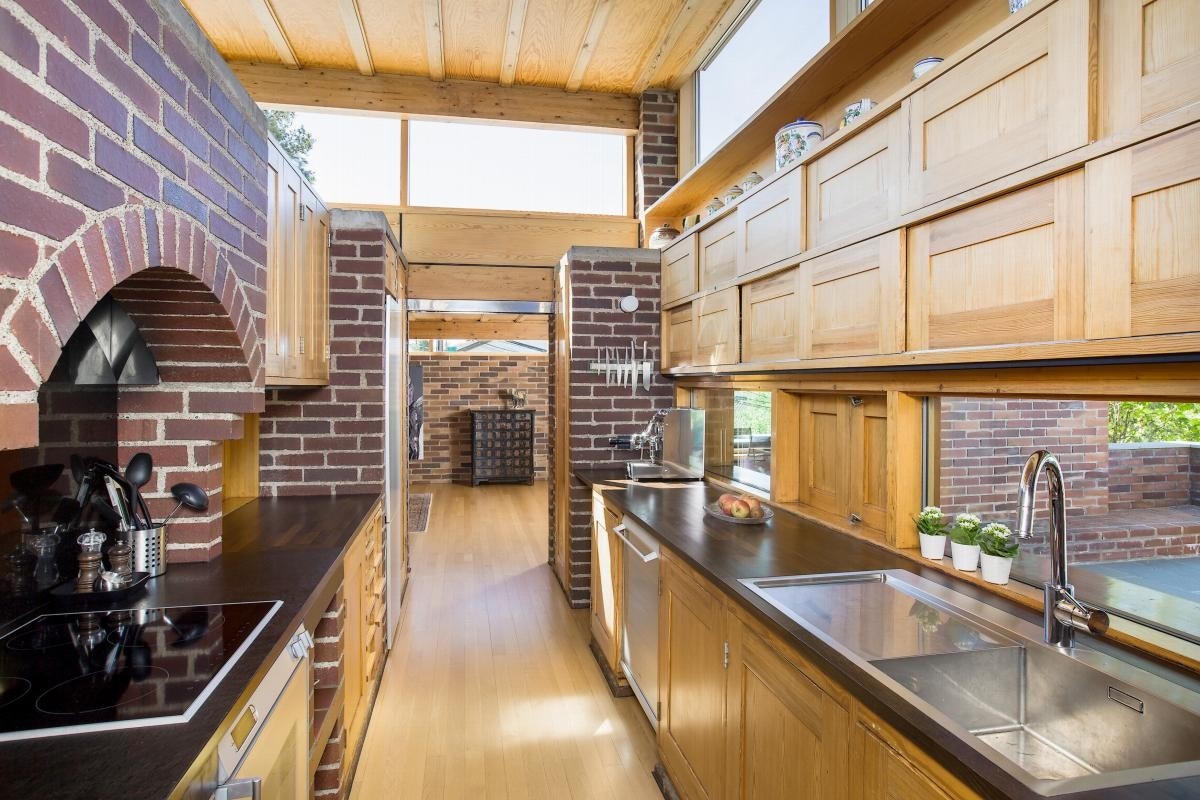 Kjøkkenet ligger midt i boligen med direkte adkomst til stuen på den ene siden og spisestuen på den andre siden Galleribilde