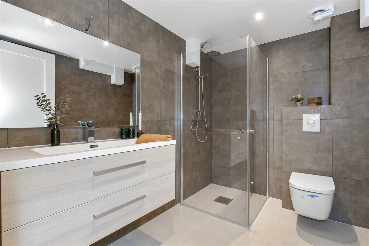 Badet i andre etasje er lekkert, romslig og velinnredet. Rommet har lyse fliser på gulv med gulvvarme, mørke fliser på veggene og downlights i himling. Galleribilde