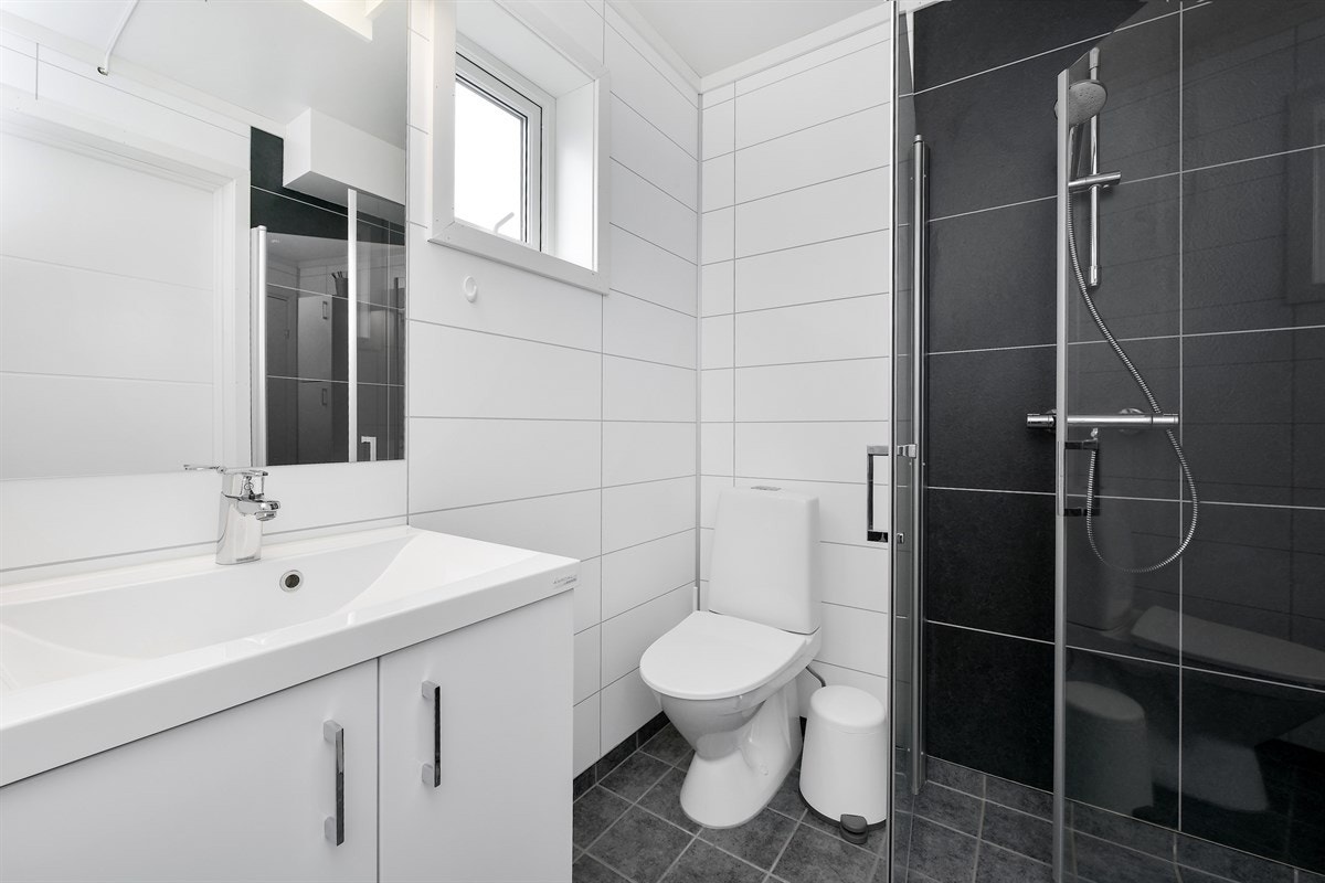 Leiligheten har også et pent bad med mørke fliser på gulv, lyse baderomsplater på vegger og lysinnslipp fra høytsittende vindu. Galleribilde