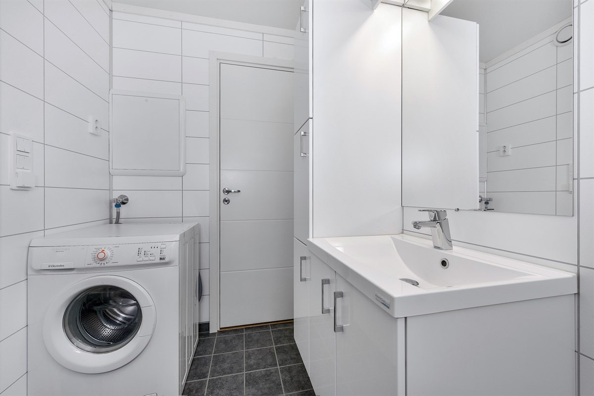 Videre har badet et frittstående toalett, dusjhjørne med innfellbare glassdører og opplegg for vaskemaskin. Galleribilde