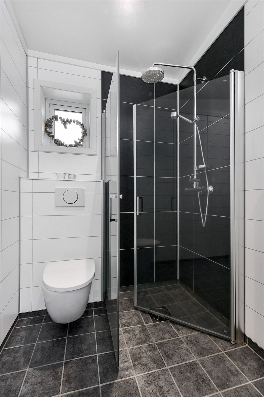 Hovedboligen inneholder to delikate bad, begge med mørke gulvfliser, hvite baderomsplater i flisimitasjon, gulvvarme og downlights. Galleribilde