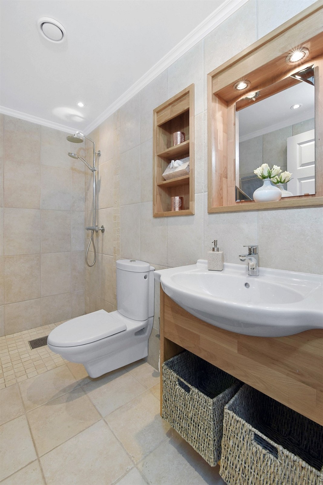 Badet i første etasje har sandfargede fliser på gulv og vegger, mosaikkfliser på gulv i dusjsonen, samt gulvvarme og downlights. Galleribilde