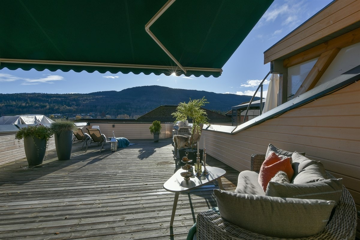 Fra stuen er det utgang til en sydvendt takterrasse på 65 kvm med vidstrakt utsikt over Elveparken og mot Eikerbygdene - et perfekt sted for å nyte deilige solfylte sommerdager. Galleribilde