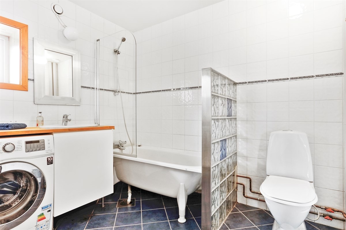 Bad med fliser på gulv, opplegg for vaskemaskin og trommel. Galleribilde