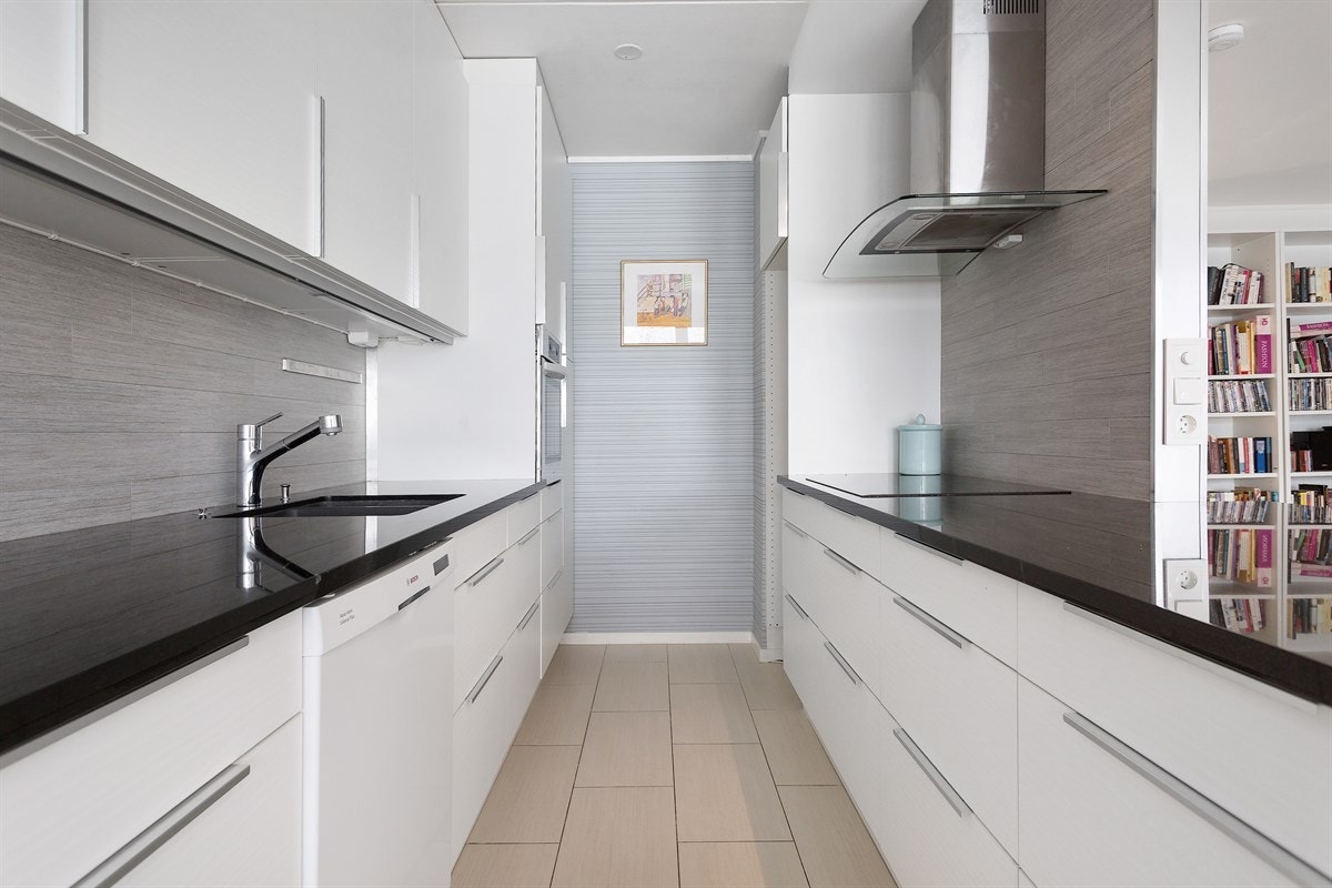 Hvit IKEA takhøy kjøkkeninnredning med takoppforing og belysning under overskap. Galleribilde