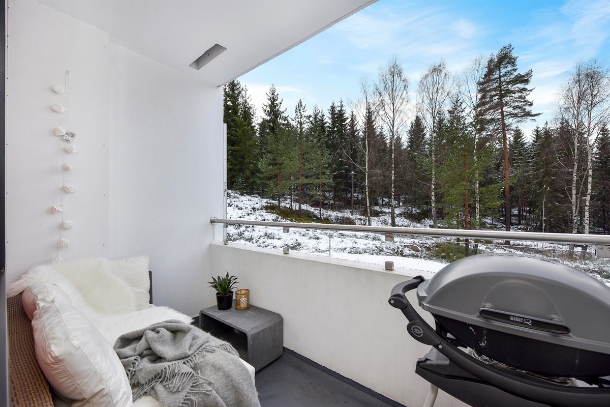 Leiligheten har en overbygd balkong med hyggelig utsyn til skogsområde, og snødekte trær vinterstid. Galleribilde