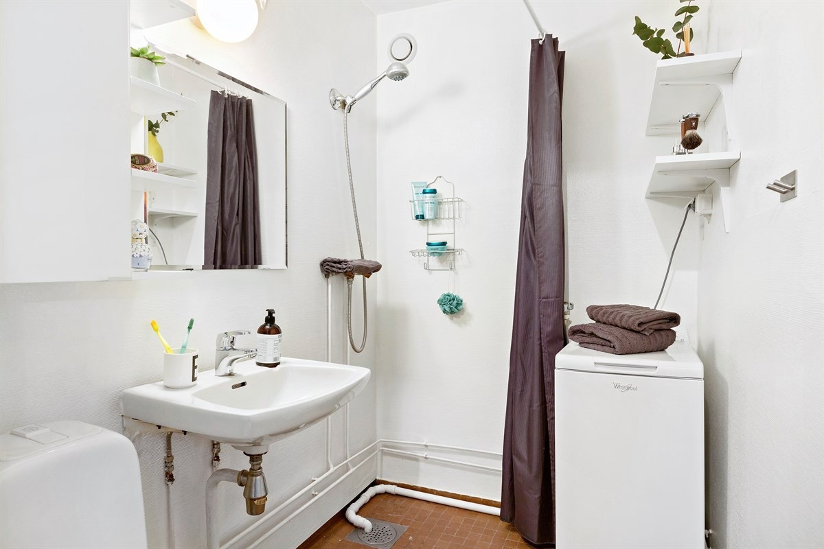 Flislagt bad med dusj, wc, servant og opplegg for vaskemaskin Galleribilde