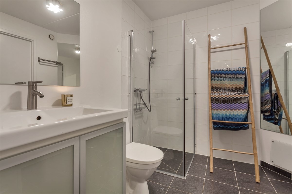 - Badet er innredet med servant med underliggende servantskap, gulvstående toalett og dusjhjørne med svingbare dusjvegger i glass - Galleribilde