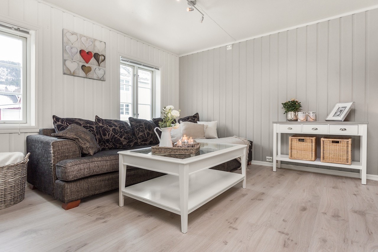 Stuen og leiligheten er hovedsakelig holdt i lys nyanse, med unntak av en brytningsvegg på stuen som gir rommet dybde Galleribilde