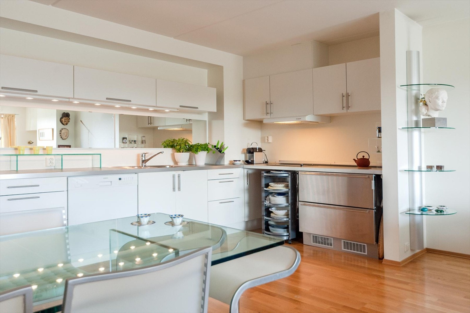 Åpen kjøkkenløsning med hvit glatt innredning, laminat benkeplate med oppvaskbeslag. Integrert platetopp (to plater), kjøleskuff og opplegg for oppvaskmaskin. Det er mulighet for å koble til stekeovn/komfyr på kjøkken Galleribilde