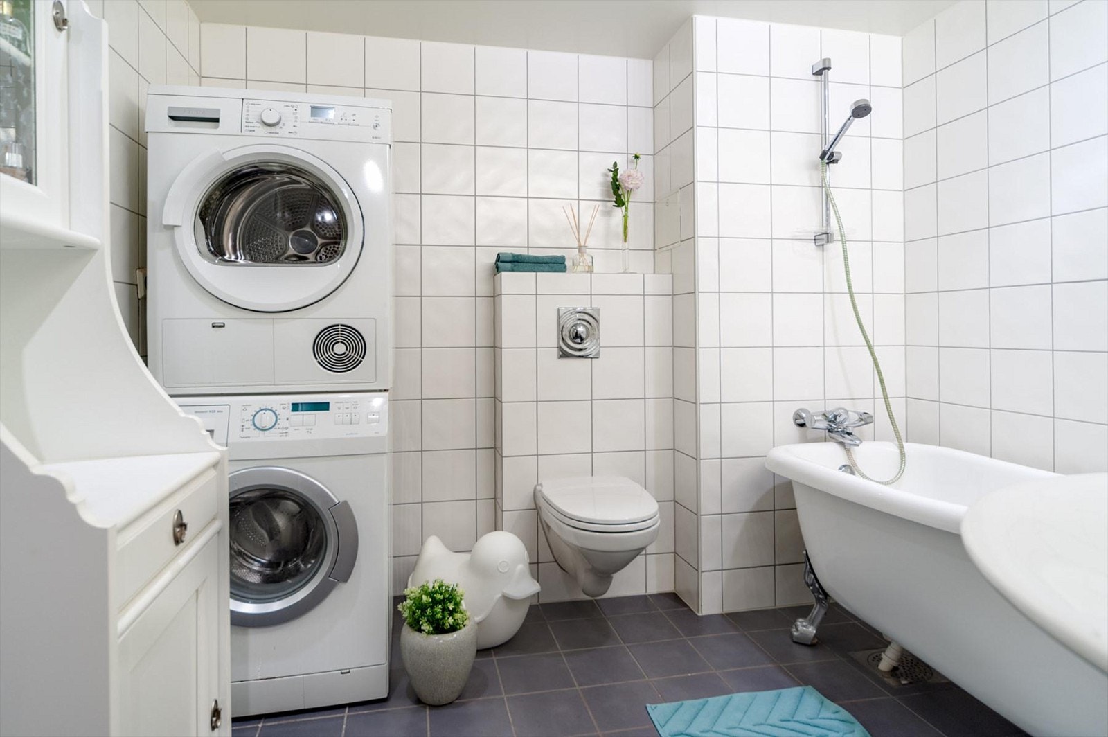 Flislagt bad med gulvvarme innredet med servant, speil med lys, vegghengt toalett og frittstående badekar. Opplegg for vaskemaskin. Galleribilde