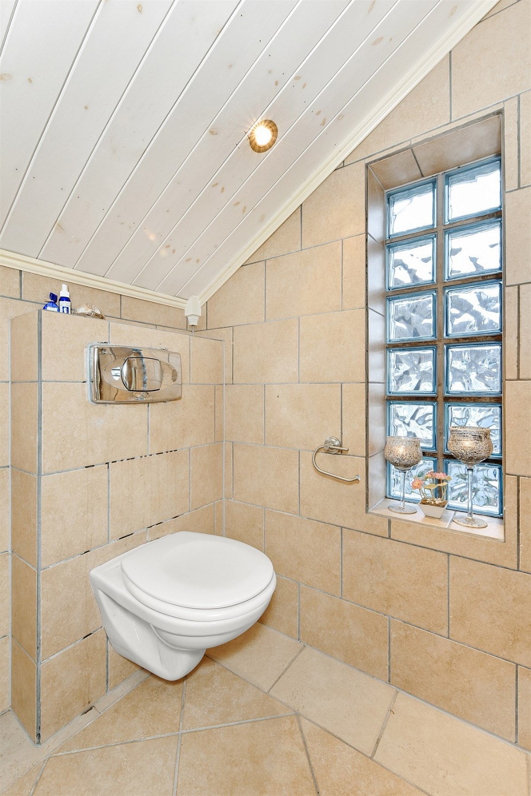 Badet har beige fliser på gulv og vegger, gulvvarme, downlights og elektrisk avtrekksvifte. Galleribilde
