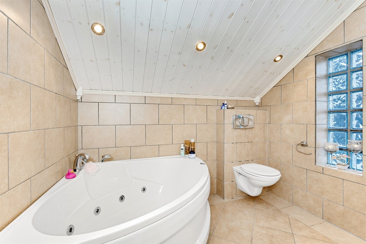 Badet har veggmontert toalett og et deilig hjørnebadekar for ekstra nytelse og velvære. Galleribilde