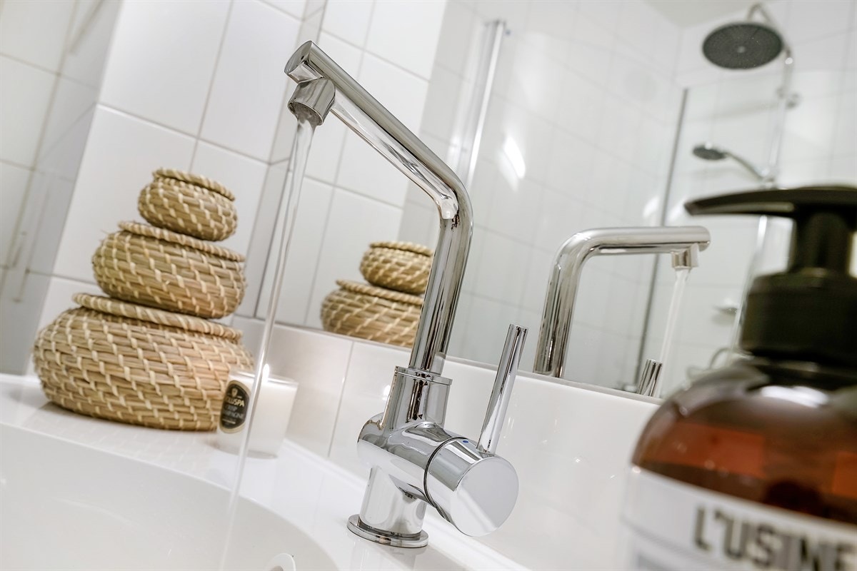 Servantskap med høyglansfronter med heldekkende servant og speil og lysarmatur på vegg over servant. Galleribilde