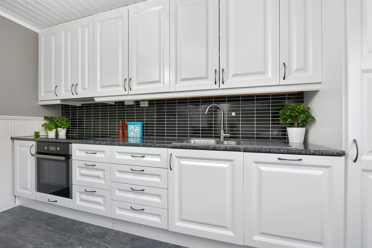 Innredningen har takhøye skap med lyse profilerte fronter og tre vitrineskap med downlights. Galleribilde