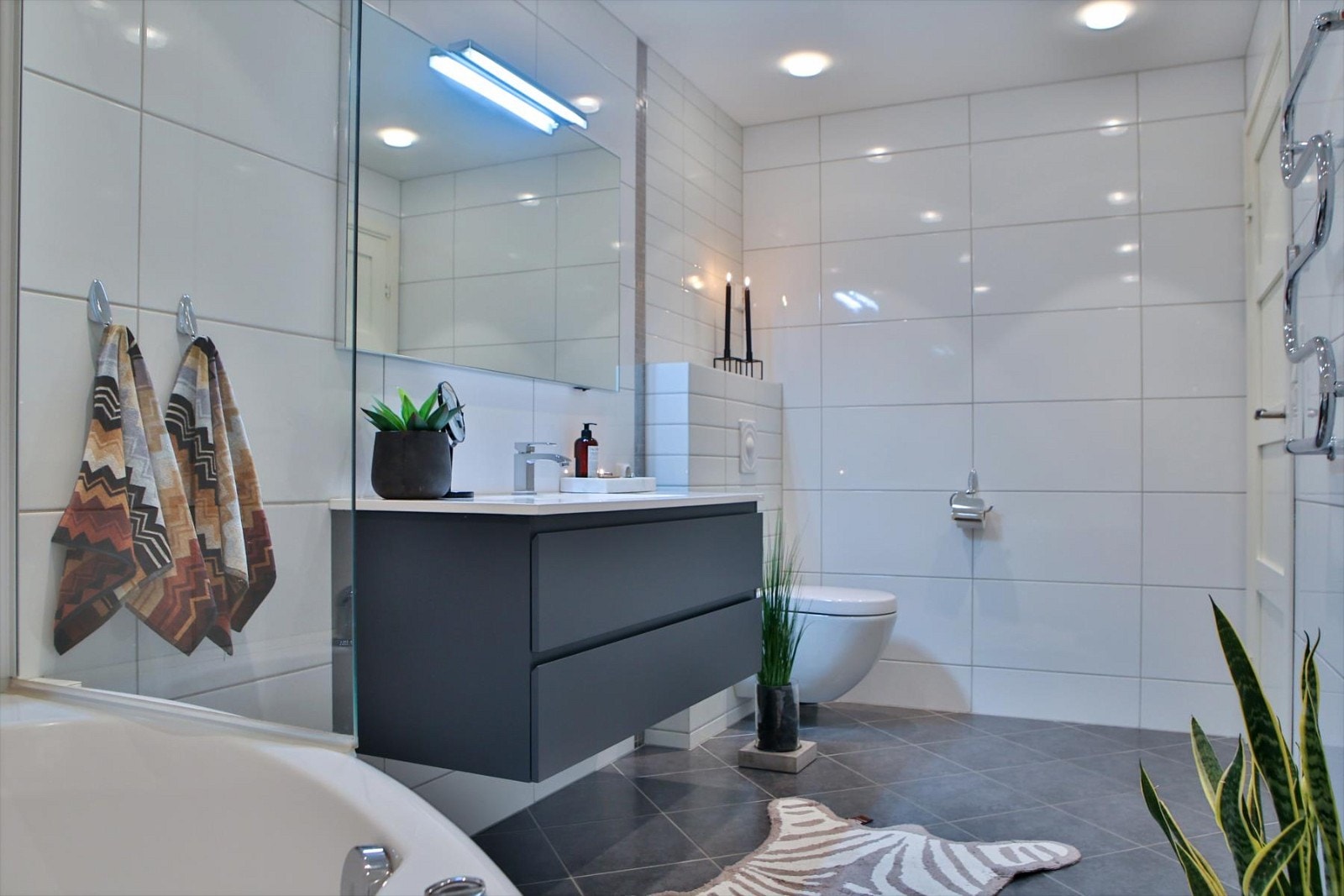 Badet har fliser på gulv og vegger. Varmekabler i gulvet og integrert Bang & Olufsen anlegg i taket. Galleribilde