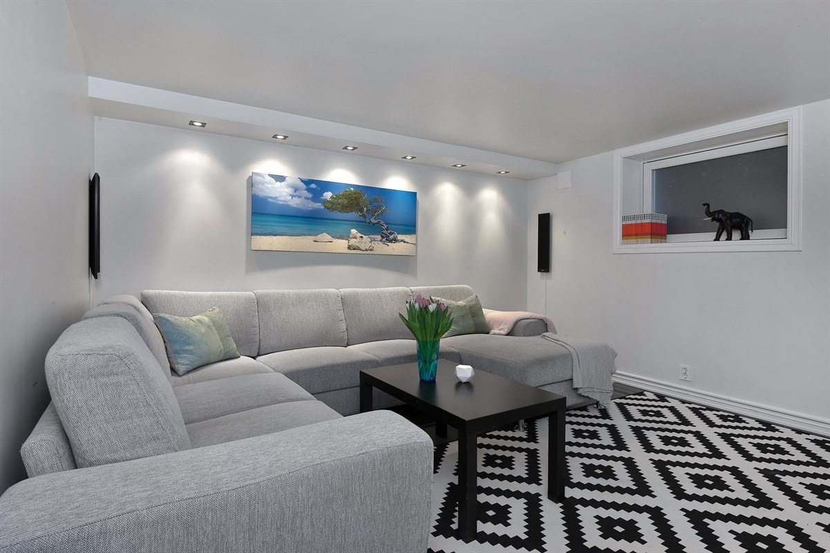 Stuen som gir et tiltalende inntrykk med mørke fliser på gulv, lyse vegger, gulvvarme og downlights i kasser langs to sider av himling. Galleribilde