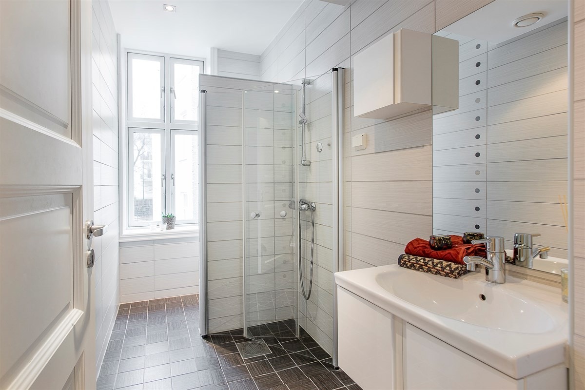 Delikat bad med dusj, vegghengt wc, servant og opplegg til vaskemaskin Galleribilde