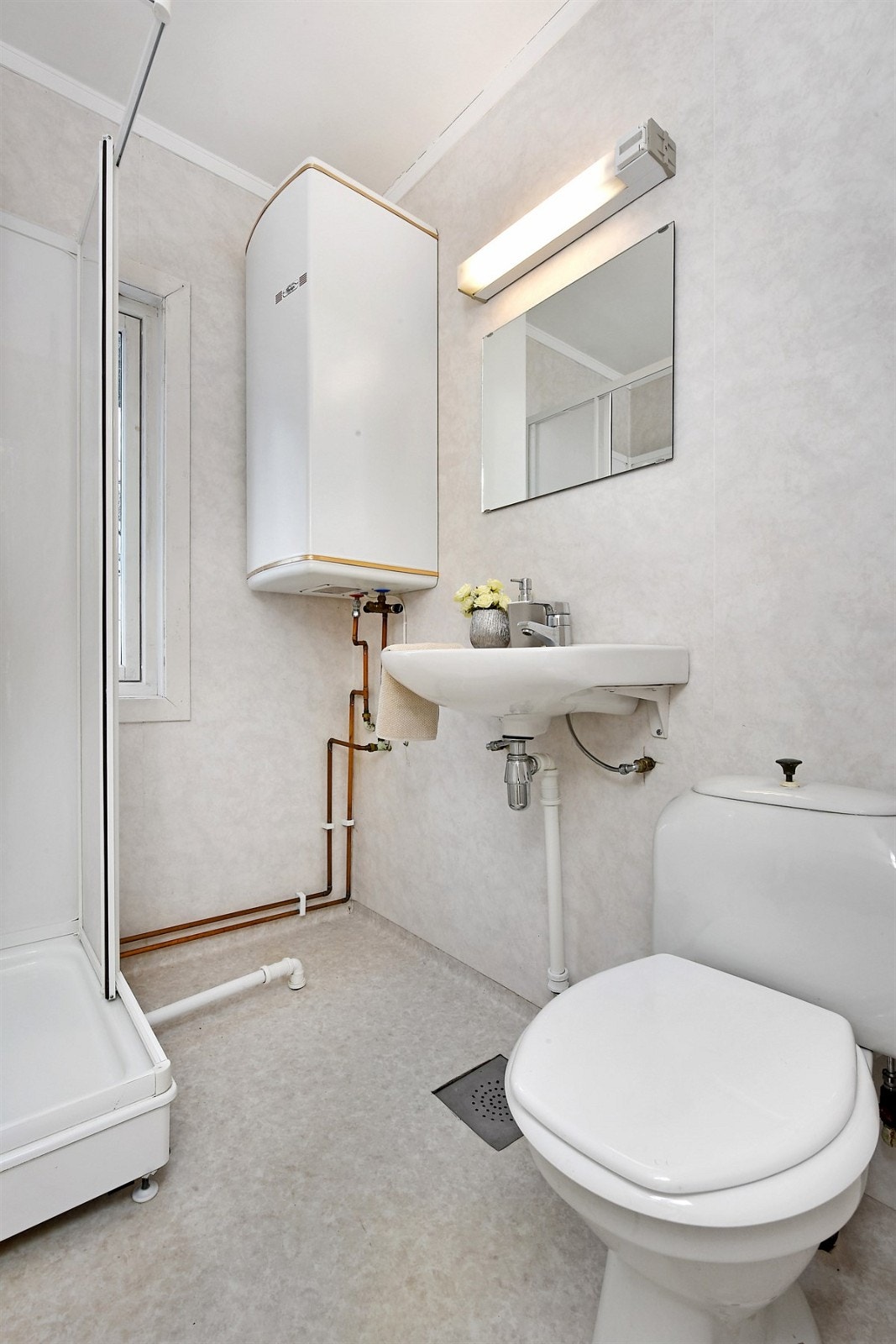 Badet har gråfarget belegg på gulv, matchende baderomstapet på veggene og lysinnslipp fra et vindu. Galleribilde