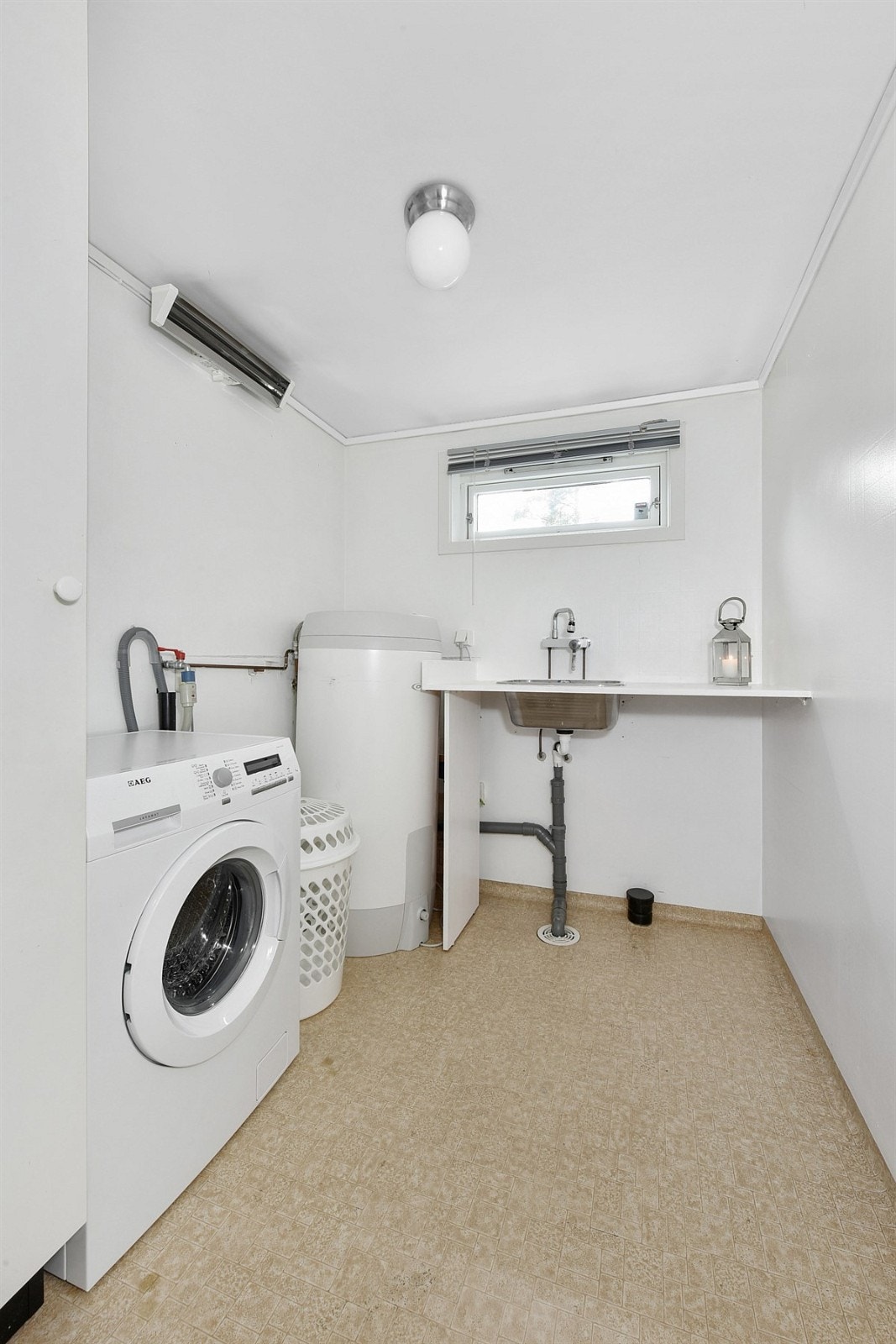 Vaskerommet er praktisk og har belegg på gulv, lyse veggflater, vindu, sluk og stråleovn. Galleribilde