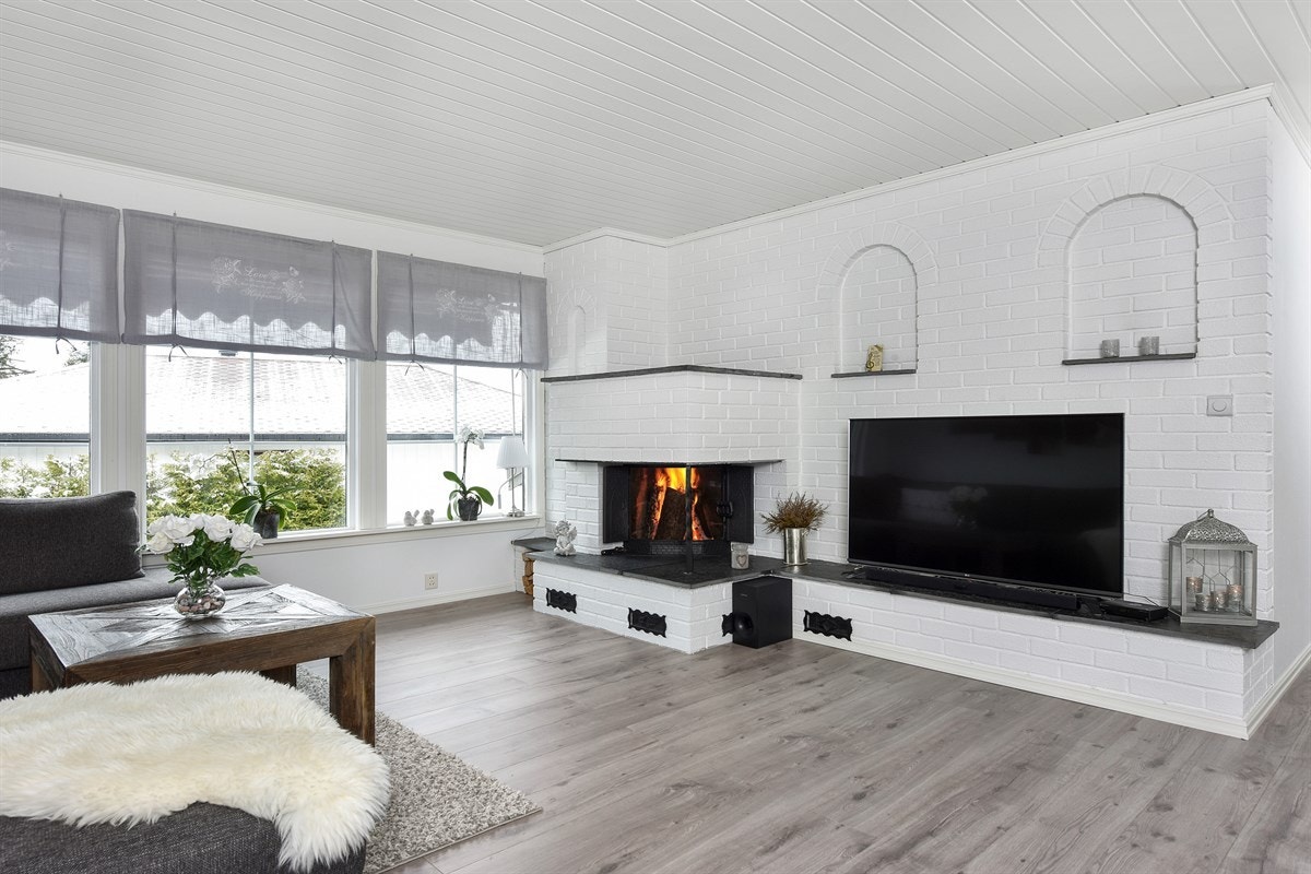 Stuen har pent laminatgulv i enstavs utførelse, hvitmalte panelplater i himling og en lekker fondvegg i mønstertapet. Galleribilde