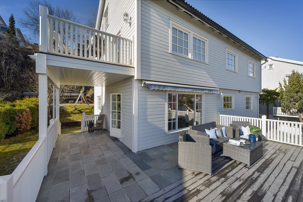 Fra stuen i første etasje er det utgang til en stor terrasse med skiferfliser og tredekke Galleribilde
