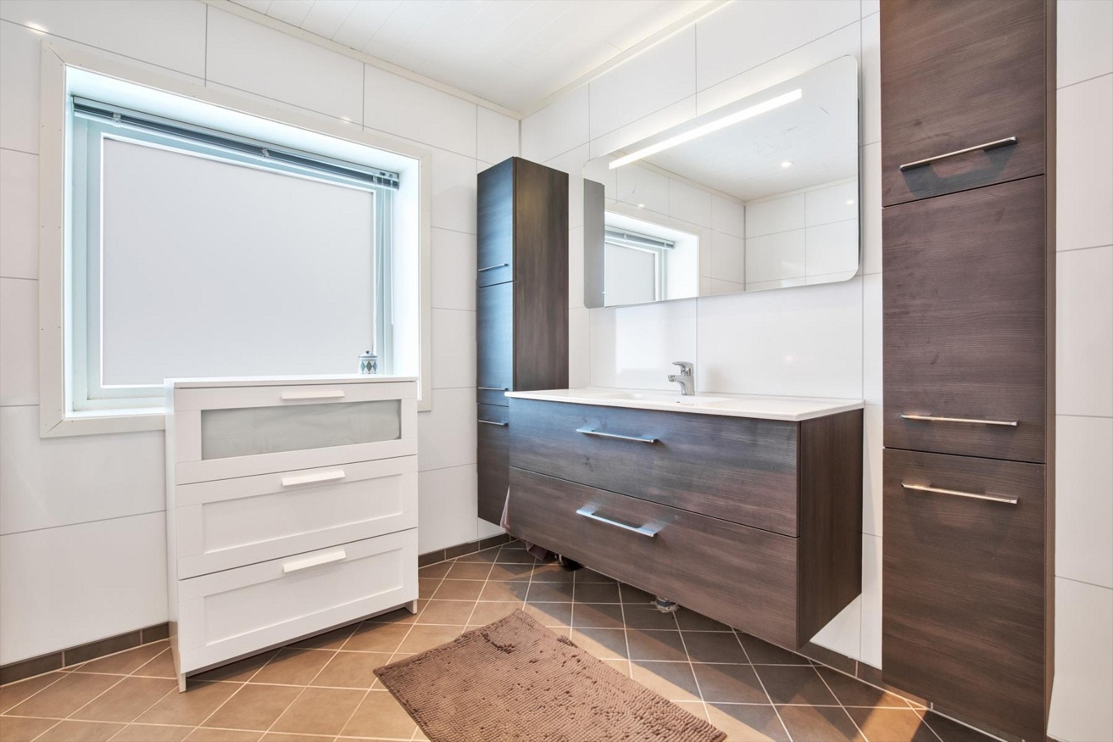 Bad i hovedetasjen, renovert i 2013. Fliser på gulv med varmekabler og baderomsplater vegg. Innredning med store skuffer og nedfelt vask. Galleribilde