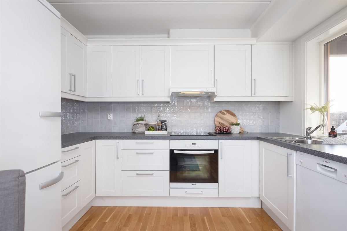 Kjøkkenet er pent og fremstår som moderne med hvite profilerte fronter og integrerte hvitevarer Galleribilde