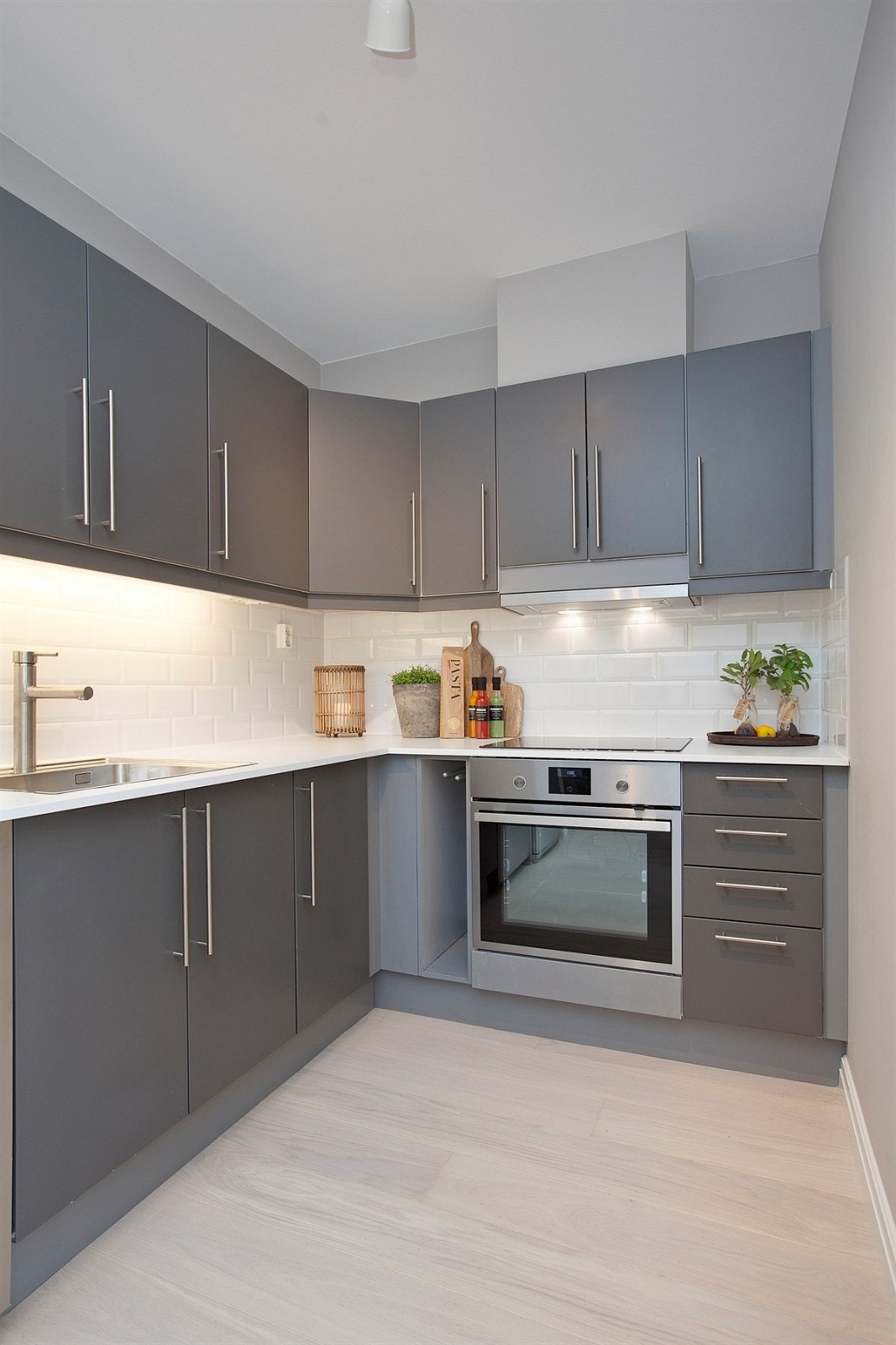 Stilrent kjøkken med slette fronter. Hvitlaserte fliser over benk. Galleribilde