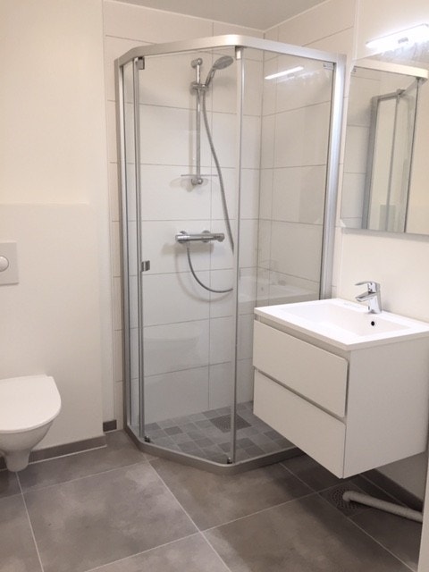 Bad med fliser på gulv og i dusjsone, vegghengt wc, opplegg for vaskemaskin Galleribilde