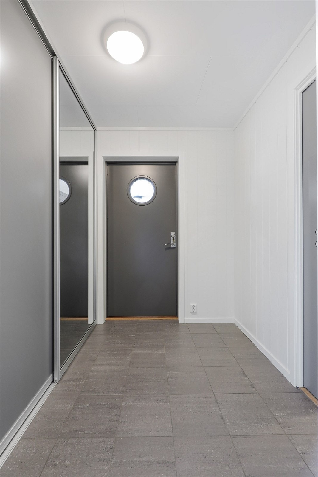 Innbydende entrè med fliser på gulv og skyvedørsgarderobe. Galleribilde