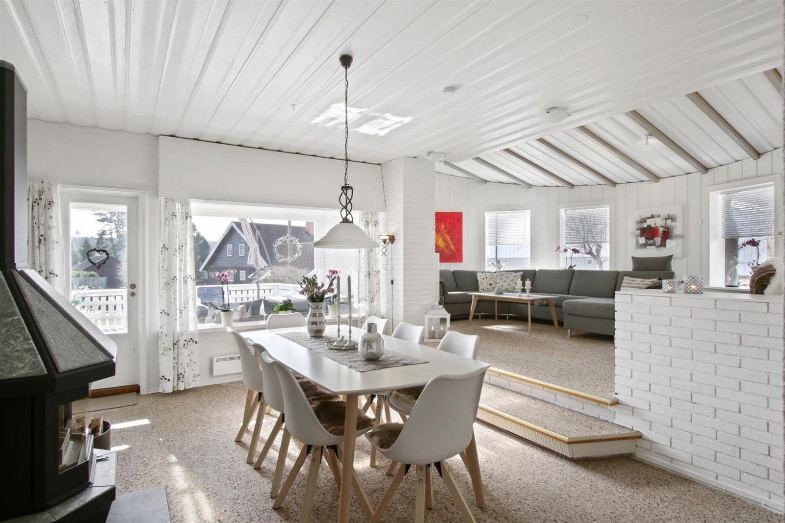 Stor stue med lyse overflater og en god klebersteins- peisovn som gir god varme og flott lys. Galleribilde