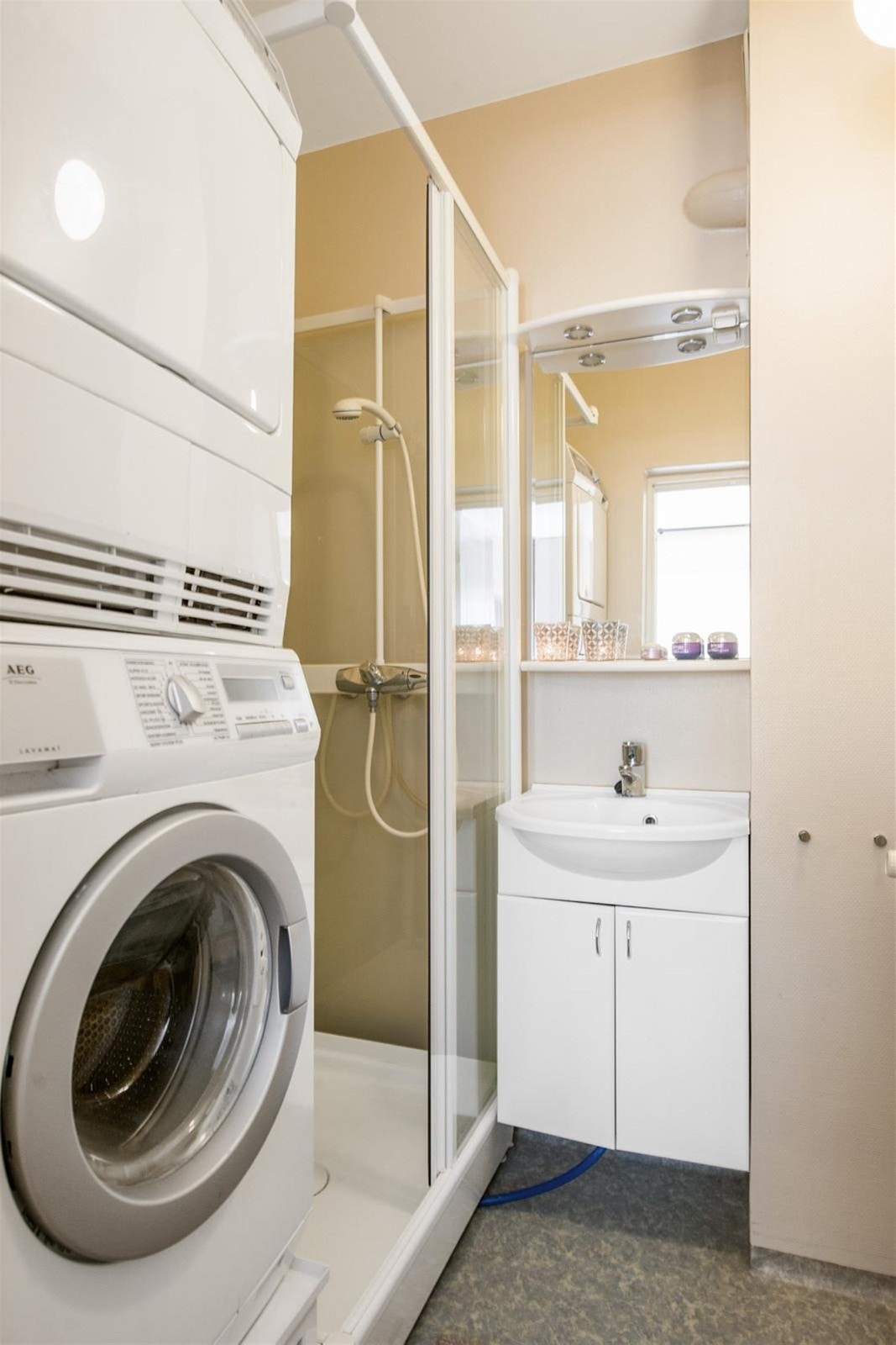 Bad med lukket dusjkabinett og opplegg for vaskemaskin Galleribilde