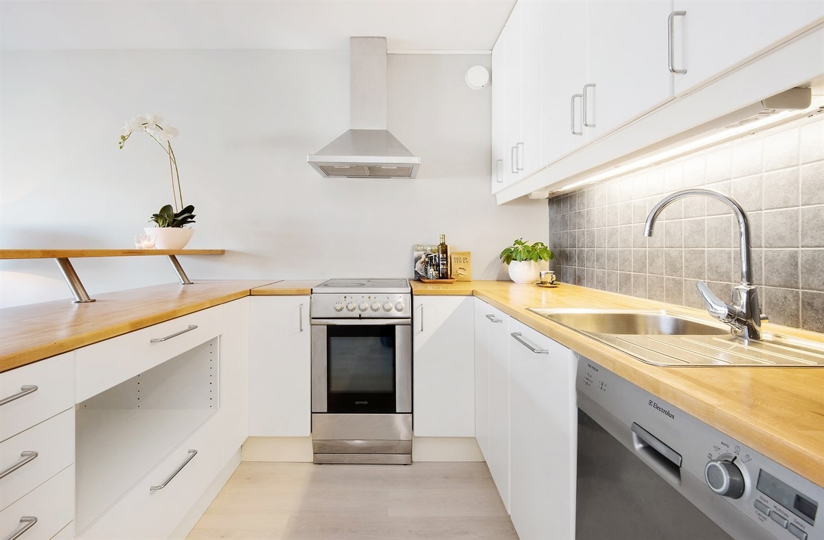 Videre har kjøkkenet glatte skapfronter og pene fliser mellom benkeplate og overskap. Galleribilde