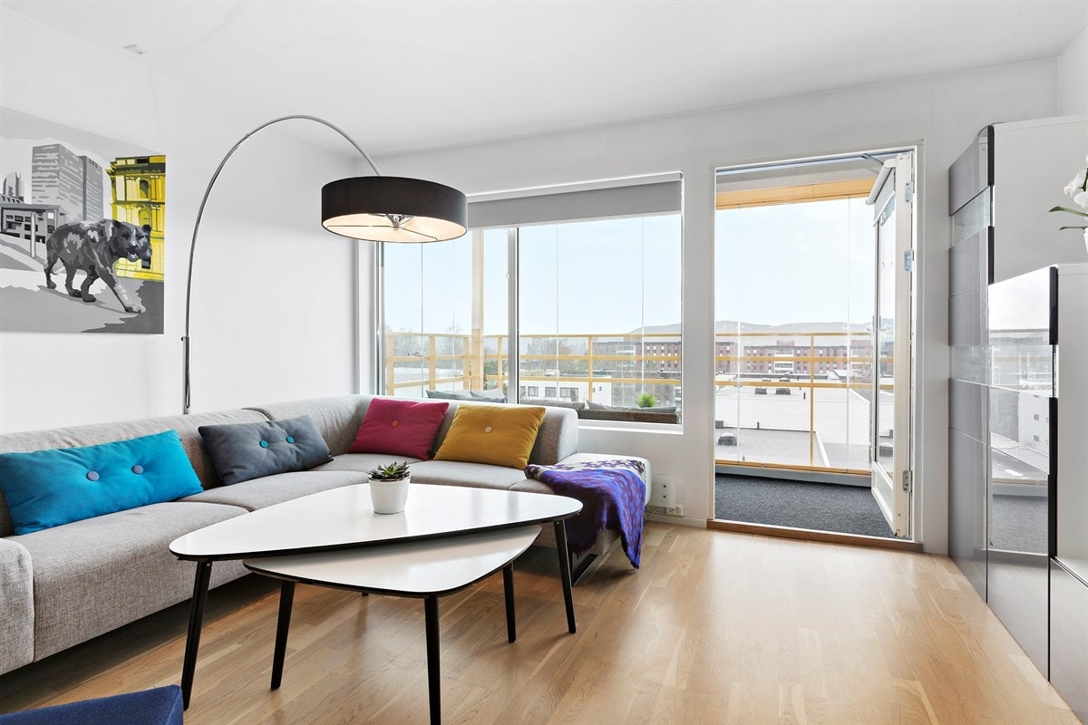 Boligen har en romslig stue med store vindusflater som slipper inn rikelig med naturlig lys og skaper en hyggelig atmosfære Galleribilde